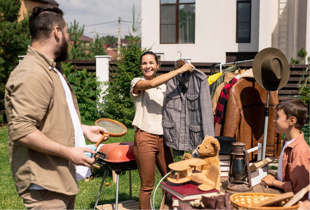 People at a garage sale checking clothes on a rail