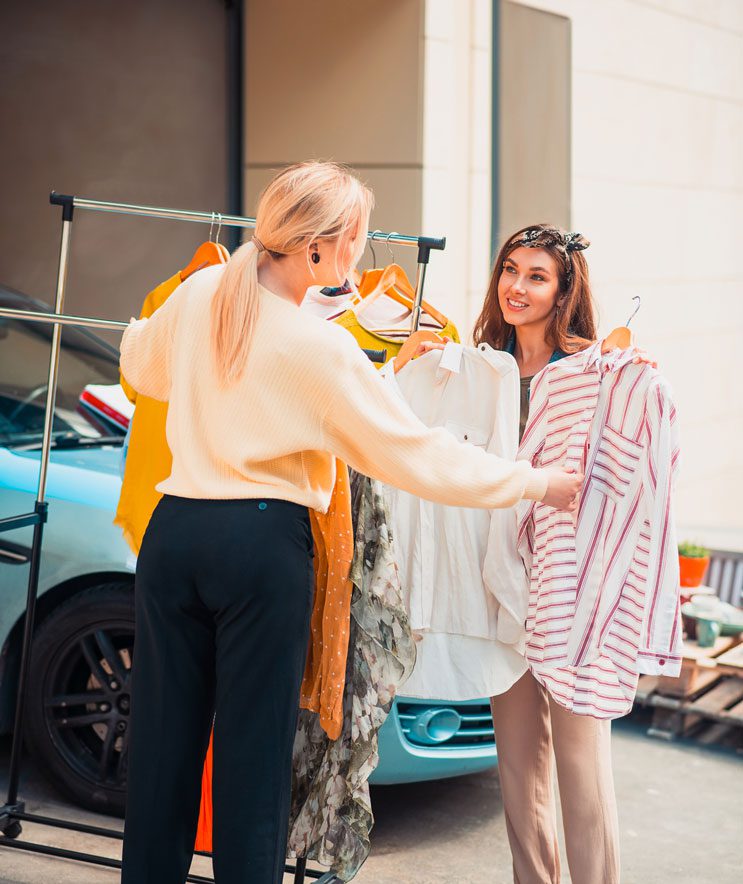 garage sale, two women looking at clothes on a rail