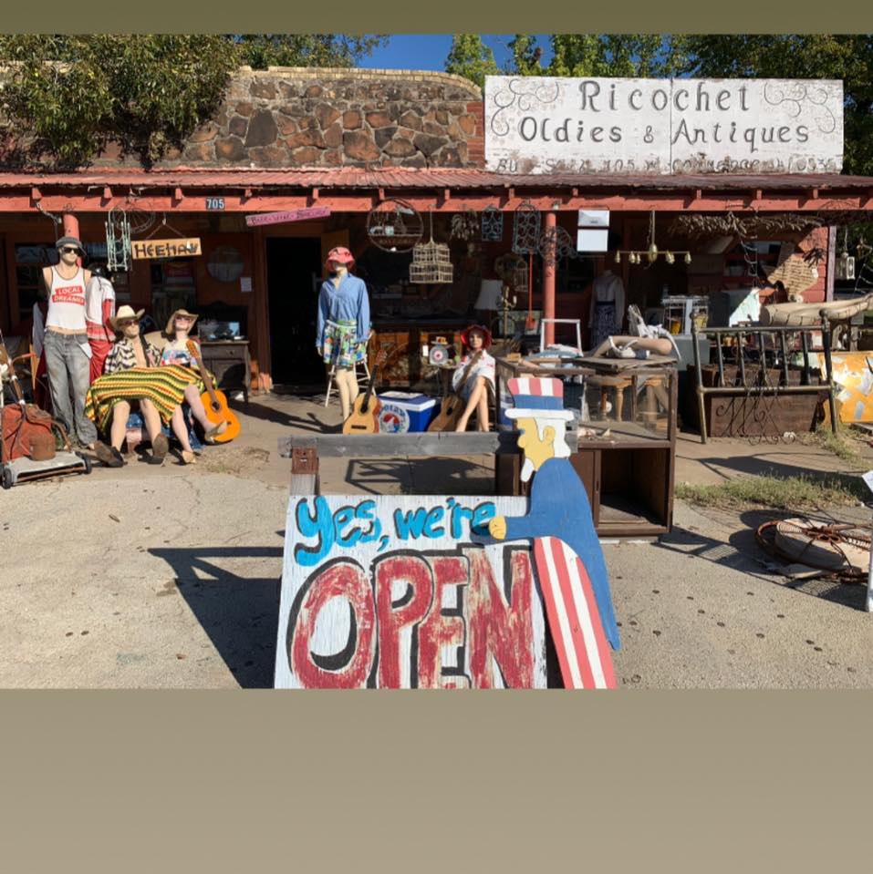Outdoor antique shop with open sign displayed.
