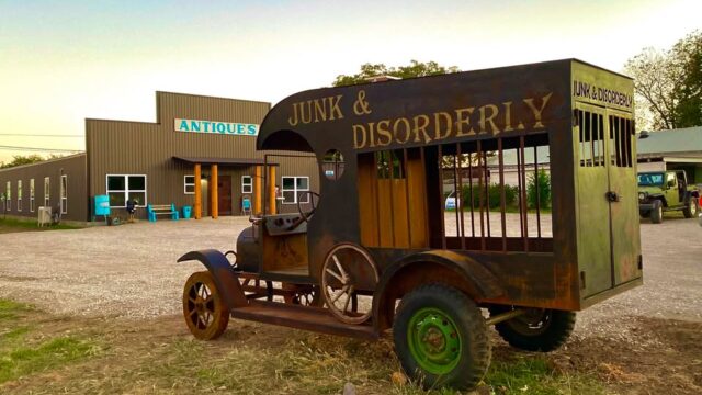 Vintage vehicle outside antique store.