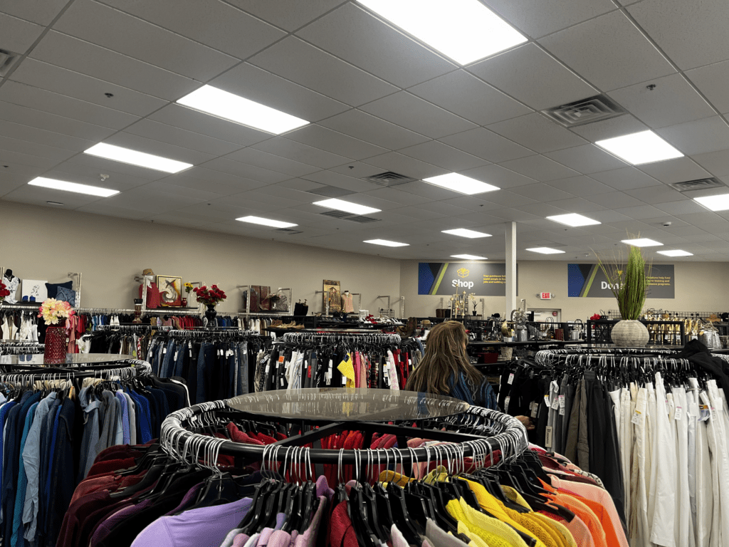 Thrift store clothing racks and bright lighting.